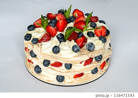 Cake with strawberries, blueberries and mint leaves on whipped cream and meringue. Close-up. Selected focus. 116471593