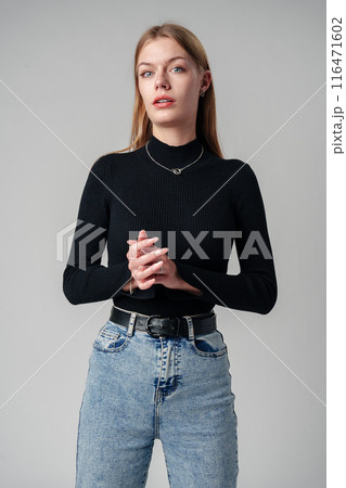 Young Woman Wearing Black Top and Jeans against gray background Young Woman Wearing Black Top and Jeans against gray background 116471602