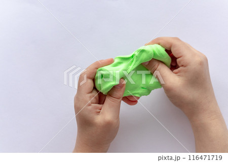 The child sculpts green plasticine with his hands. 116471719