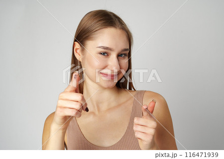 Young Woman Pointing Towards Camera With a Playful Expression in a Studio 116471939
