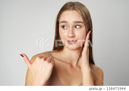 Young Woman in Tank Top Pointing at Something on gray background Young Woman in Tank Top Pointing at Something on gray background 116471944