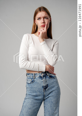 Young Woman Holding Hand to Face on gray background Young Woman Holding Hand to Face on gray background 116471991