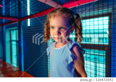 Young Girl With Curly Hair Exploring an Indoor Play Area During Evening Hours 116472041