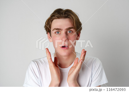 Young Man With Surprised Expression and Hands Raised in Studio Setting Young Man With Surprised Expression and Hands Raised in Studio Setting 116472093