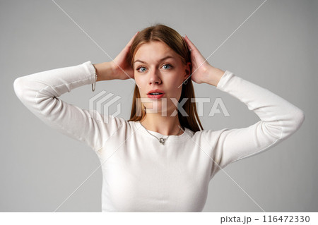 Young Woman Expressing Surprise or Confusion Against a Grey Background Young Woman Expressing Surprise or Confusion Against a Grey Background 116472330