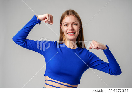 Smiling Young Woman in Blue Top Celebrating Success With Raised Fist Smiling Young Woman in Blue Top Celebrating Success With Raised Fist 116472331