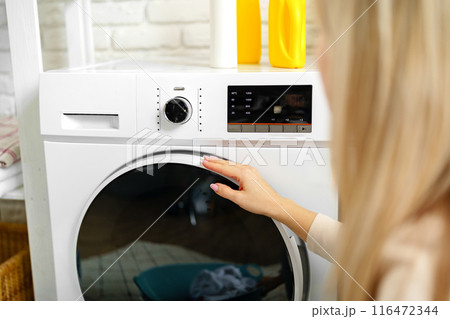 Woman Setting Washing Machine Cycle in Laundry Room Woman Setting Washing Machine Cycle in Laundry Room 116472344