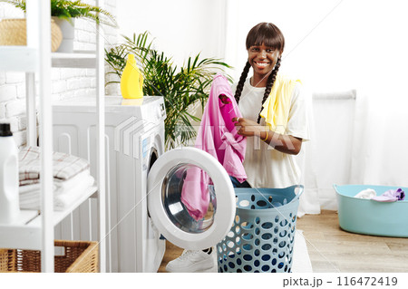 African Woman Folding Laundry After Washing Clothes in Modern Laundry Room African Woman Folding Laundry After Washing Clothes in Modern Laundry Room 116472419