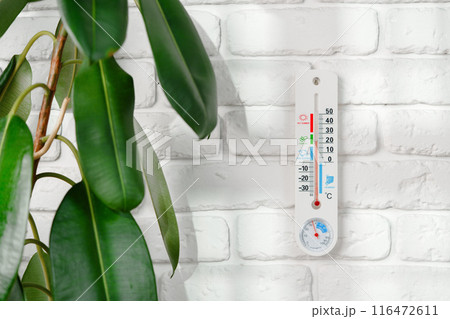 White Thermometer Mounted on a White Brick Wall 116472611