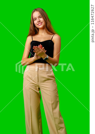Young Woman Standing With Folded Hands against green background 116472627