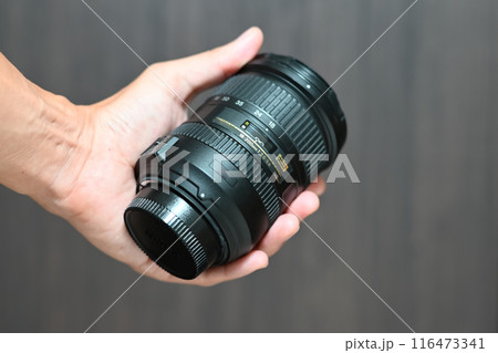 男の手に持ったカメラレンズ 116473341