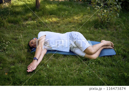 a man performs somatic exercises in the garden in the morning 116473874