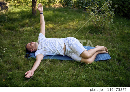 a man performs somatic exercises in the garden in the morning 116473875