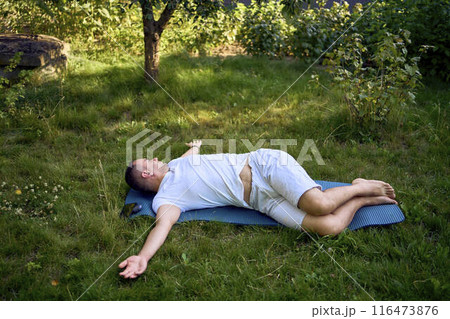 a man performs somatic exercises in the garden in the morning a man performs somatic exercises in the garden in the morning 116473876