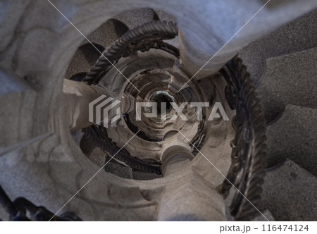 Upside view of The old stone spiral staircase with iron railing inside columnar structures. Upside view of The old stone spiral staircase with iron railing inside columnar structures. 116474124