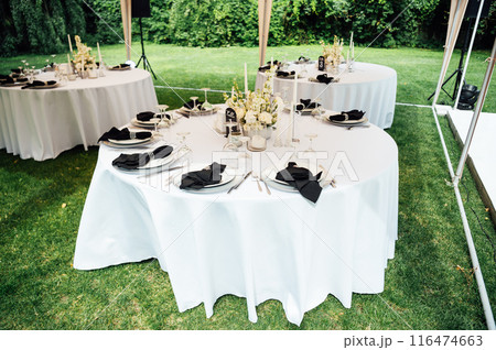 Open -air wedding banquet. The table is decorated with white plates and premium glasses for wine 116474663