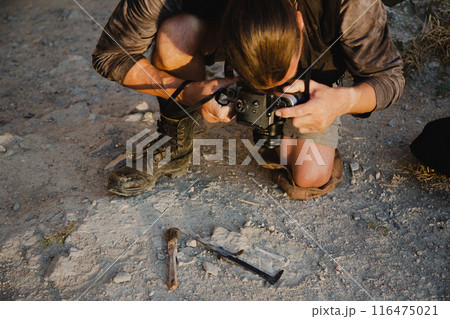 Historical reconstruction of an archaeological expedition of the mid-19th century. Concept for a history channel. An archaeologist takes a photo of a found artifact 116475021