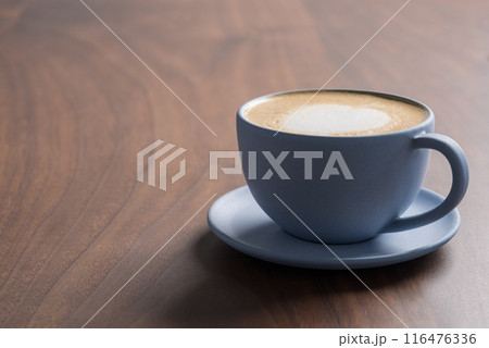 Fresh cappuccino in a blue cup on walnut table with copy space Fresh cappuccino in a blue cup on walnut table with copy space 116476336