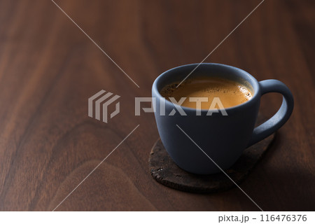Fresh espresso in a blue cup on walnut table with copy space Fresh espresso in a blue cup on walnut table with copy space 116476376