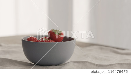 fresh strawberries from blue bowl on linen cloth 116476476