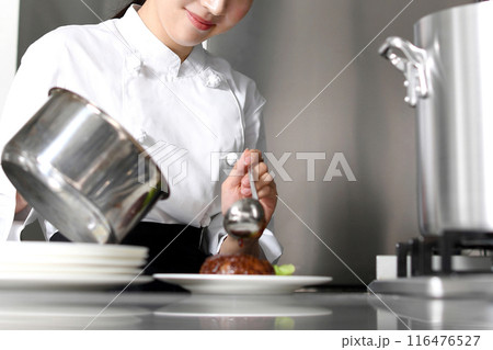料理を皿に盛り付ける若いアジア人の女性調理師 料理を皿に盛り付ける若いアジア人の女性調理師 116476527