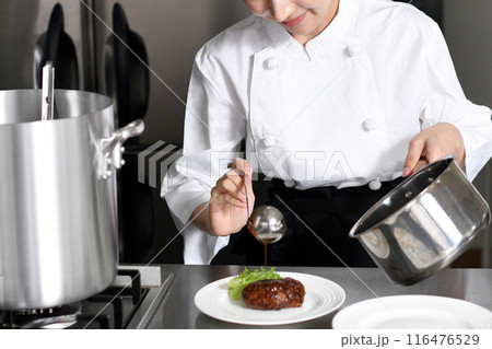 料理を皿に盛り付ける若いアジア人の女性調理師 116476529