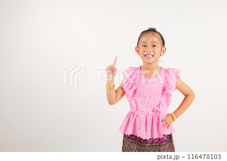 Portrait Thailand kid girl smiling traditional Thai dress costume makes gesture fingers point upwards above presenting product something, studio isolated white background, kindergarten child man smile 116478103