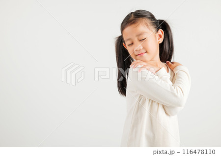Happy young child smiling Asian girl hugging herself remember a moment studio short isolated on white background, Self care and self esteem concept, Lifestyle kindergarten kid love yourself carefree 116478110