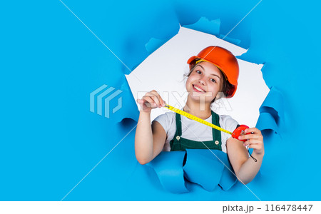 cheerful child laborer using building uniform and tape measure, copy space, labor day 116478447