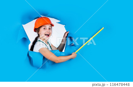 happy kid engineer with tape measure tool in hard hat, workshop 116478448