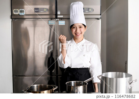 調理場でガッツポーズをする若い女性調理師 116478682