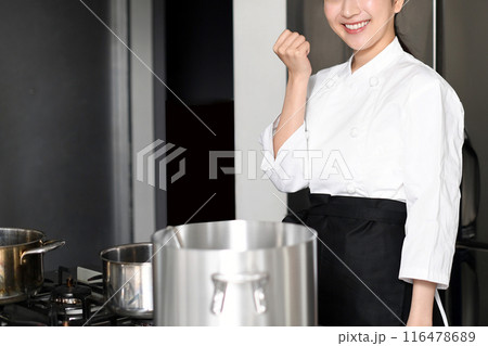 調理場でガッツポーズをする若い女性調理師 116478689