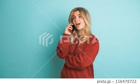 Happy woman talking on mobile phone in blue studio Happy woman talking on mobile phone in blue studio 116478722
