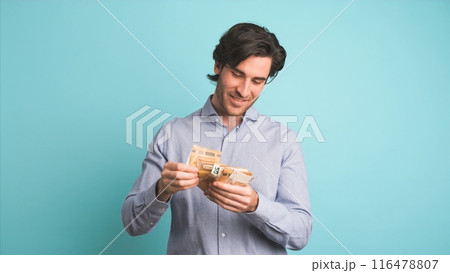 Cheerful rich man throwing around cash in blue studio Cheerful rich man throwing around cash in blue studio 116478807
