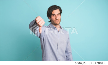 Upset man showing thumb down in blue studio 116478812