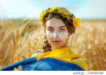 A woman wearing a flower crown poses in a wheat field under a clear sky. Ukraine's Independence Day. 116480180