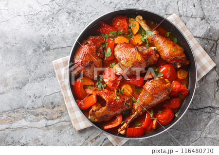 Homemade rooster stew with bell peppers, onions and carrots in a spicy tomato sauce close-up in a pan. Horizontal top view Homemade rooster stew with bell peppers, onions and carrots in a spicy tomato sauce close-up in a pan. Horizontal top view 116480710