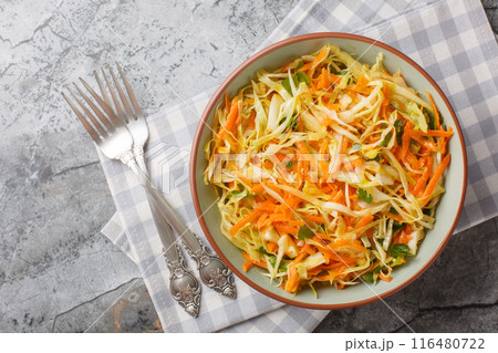 simple homemade salad of white cabbage with carrots seasoned with vinegar and olive oil close-up in a bowl. Horizontal top view simple homemade salad of white cabbage with carrots seasoned with vinegar and olive oil close-up in a bowl. Horizontal top view 116480722