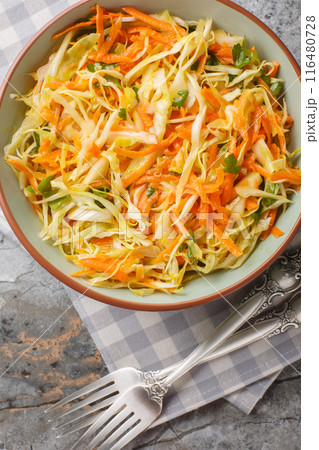 Lahanosalata Greek Cabbage Salad with carrot and parsley seasoned with olive oil closeup on the bowl. Vertical top view 116480728