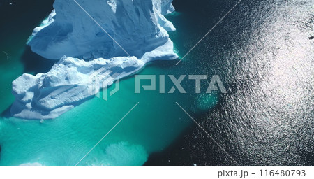 Massive iceberg melting, underwater ice formation floating turquoise ocean. Snow covered white and blue glacier under bright sun. Antarctica landscape. Global warming, climate change. 116480793