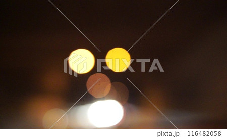 Blurred car lights bokeh in the evening city. Defocused headlights and street lighting at night. Moving bokeh circles of cars at night. Blurred city traffic background Blurred car lights bokeh in the evening city. Defocused headlights and street lighting at night. Moving bokeh circles of cars at night. Blurred city traffic background 116482058