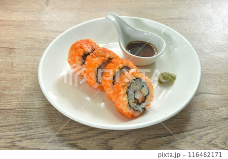 California roll topping shrimp egg stuffed maki sushi rice filling sweet egg and pickled cucumber wrapped by seaweed with wasabi dipping soy sauce on plate California roll topping shrimp egg stuffed maki sushi rice filling sweet egg and pickled cucumber wrapped by seaweed with wasabi dipping soy sauce on plate 116482171