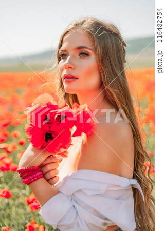 Woman poppies field. Side view of a happy woman with long hair in a poppy field and enjoying the beauty of nature in a warm summer day. 116482754