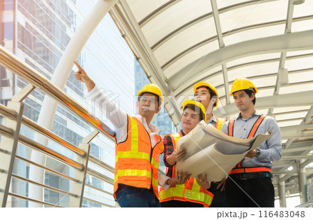 Group of Asian engineers and architects with safety helmet and safety vest working together on modern building. Construction, engineering and teamwork concept 116483048