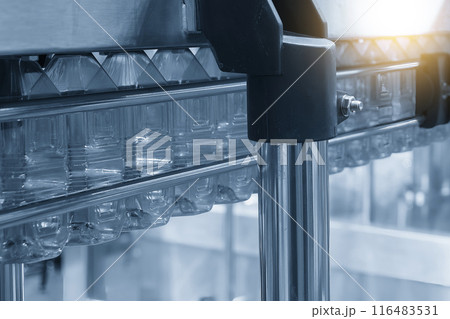 The  empty drinking water bottles  hanging on the conveyor belt for filling process. 116483531