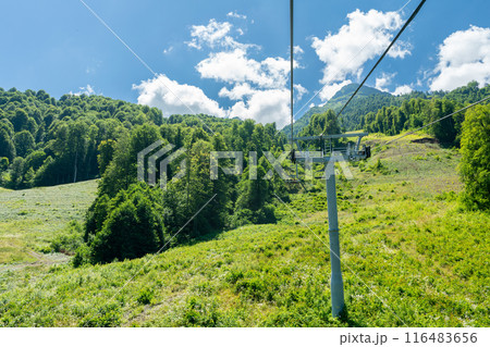 Cable car seats soar over beautiful mountains on a sunny day in Krasnaya Polyana 116483656