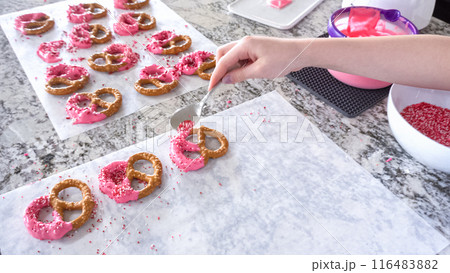 With focused attention, this budding culinary artist dips pretzels into a pot of melted chocolate, creating sweet delights in the warmth of a well-lit home kitchen. With focused attention, this budding culinary artist dips pretzels into a pot of melted chocolate, creating sweet delights in the warmth of a well-lit home kitchen. 116483882