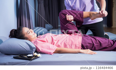 Thai massage by stretching foot and leg to woman at spa bed Thai massage by stretching foot and leg to woman at spa bed 116484466