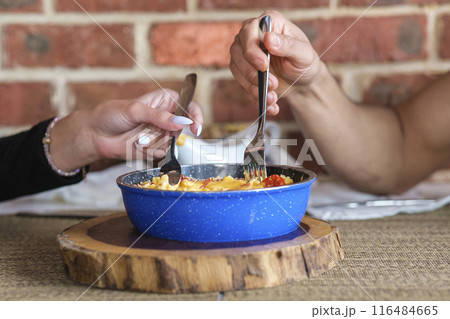 Two people are eating from the bowl 116484665
