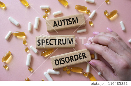 Autism Spectrum Disorder symbol. Concept word Autism Spectrum Disorder on wooden blocks. Doctor health. Beautiful pink background with pills. Medicine and Autism Spectrum Disorder concept. Copy space 116485821